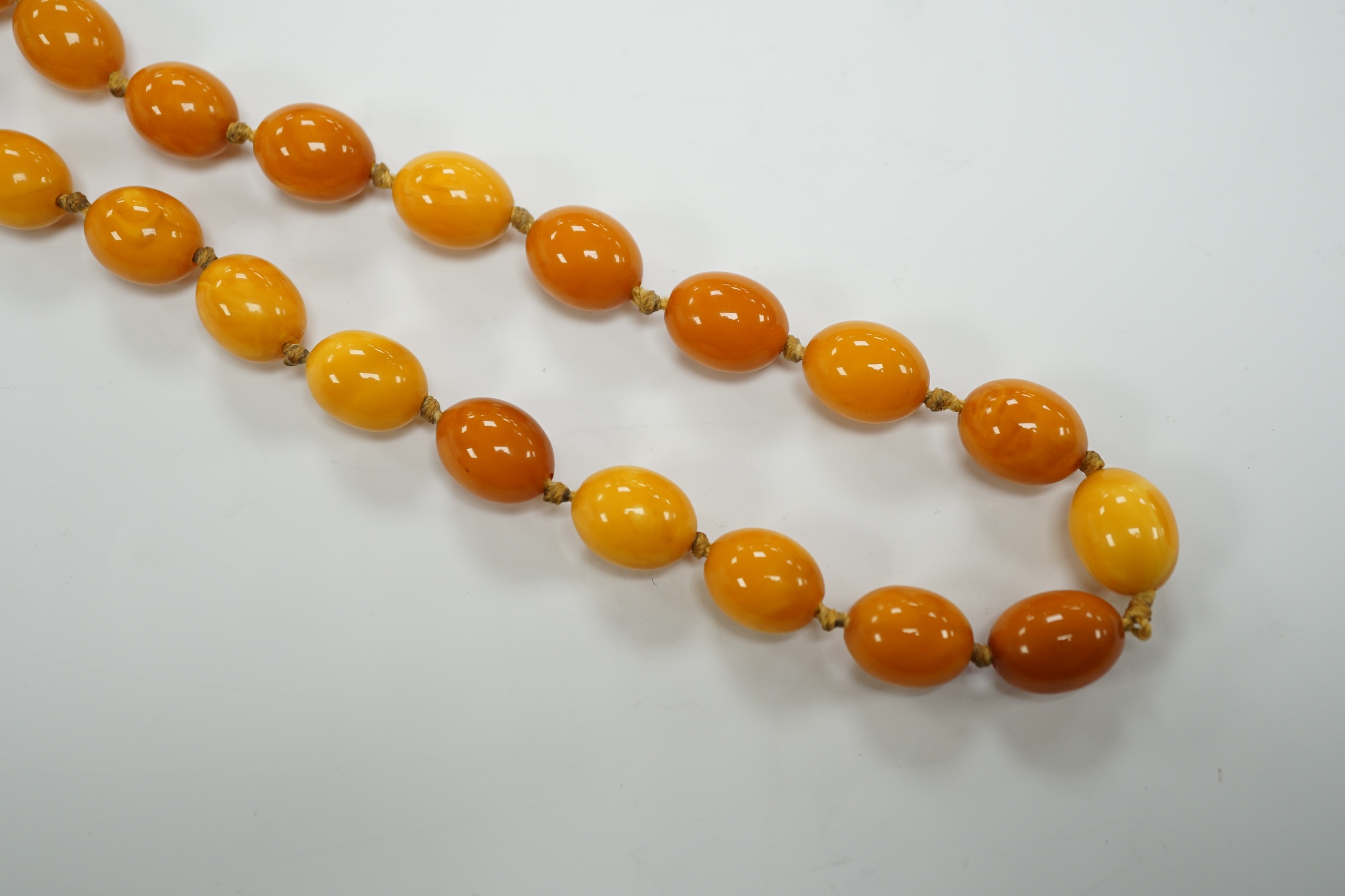 A long single strand oval amber bead necklace, 156cm, gross weight 89 grams.